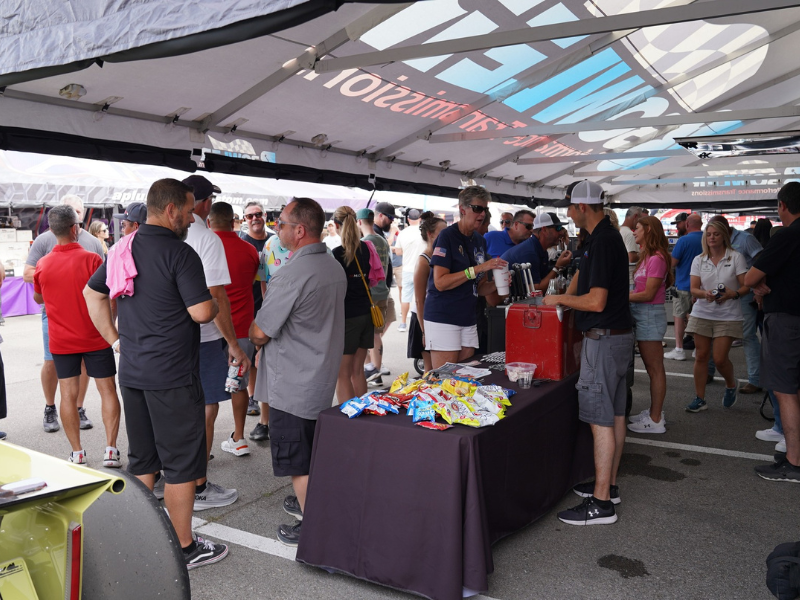 People browsing display tables under a tent canopy